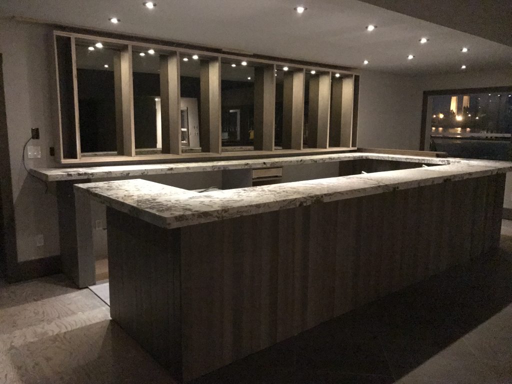 Custom interior bar with stone countertops and recessed lighting